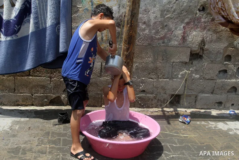 Palestinian children enjoy themselves with water during a sweltering heat wave, in Rafah in the southern Gaza strip, on August 9, 2015. Photo by Abed Rahim Khatib