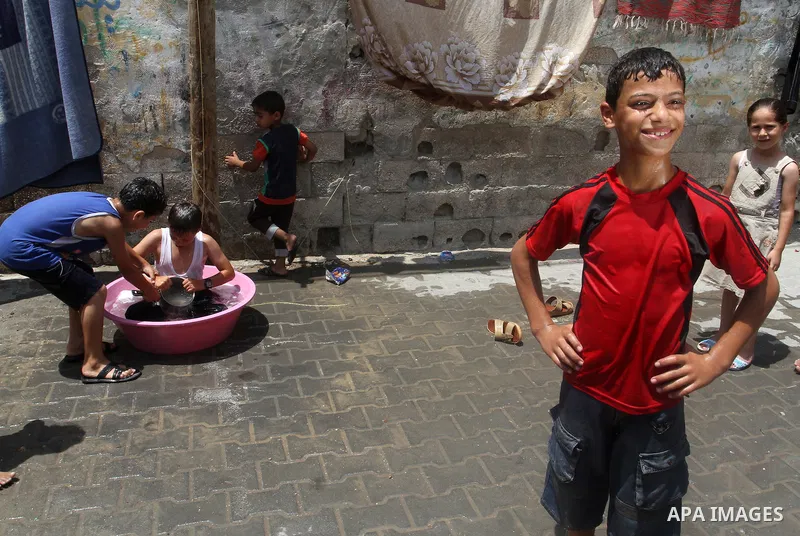 Palestinian children enjoy themselves with water during a sweltering heat wave, in Rafah in the southern Gaza strip, on August 9, 2015. Photo by Abed Rahim Khatib
