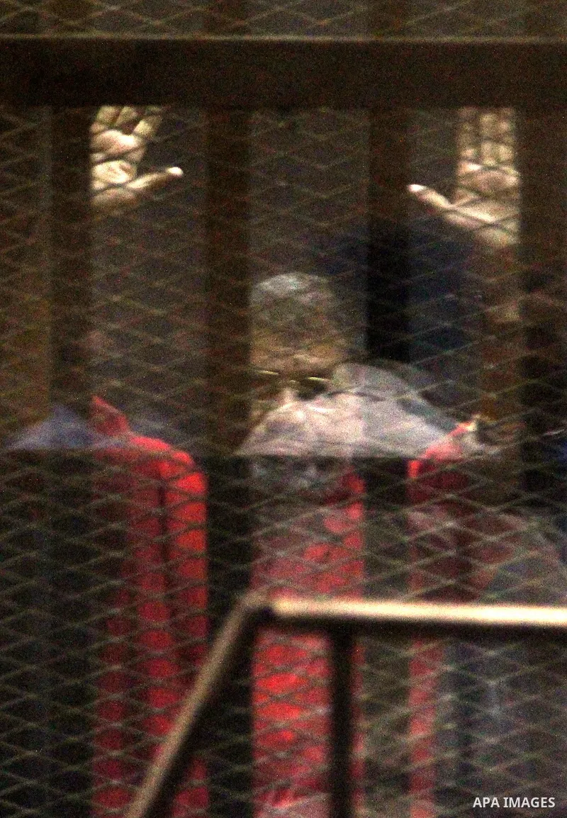 Ousted Egyptian president Mohammed Morsi waves as he stands behind bars during his trail in a court in Cairo on August 9, 2015. Cairo Criminal Court resumes on Saturday the trial of former Islamist president Mohamed Mors...