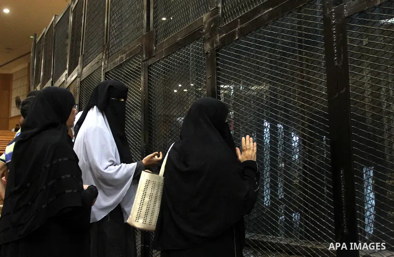 Relatives speak with Egyptian Muslim Brotherhood defendants as they stand behind the bars during their trial, along with ousted Islamist president Mohamed Morsi (unseen), in a court in Cairo on August 9, 2015. Cairo Crim...