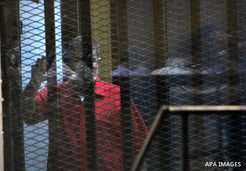 Ousted Egyptian president Mohammed Morsi waves as he stands behind bars during his trail in a court in Cairo on August 9, 2015. Cairo Criminal Court resumes on Saturday the trial of former Islamist president Mohamed Mors...