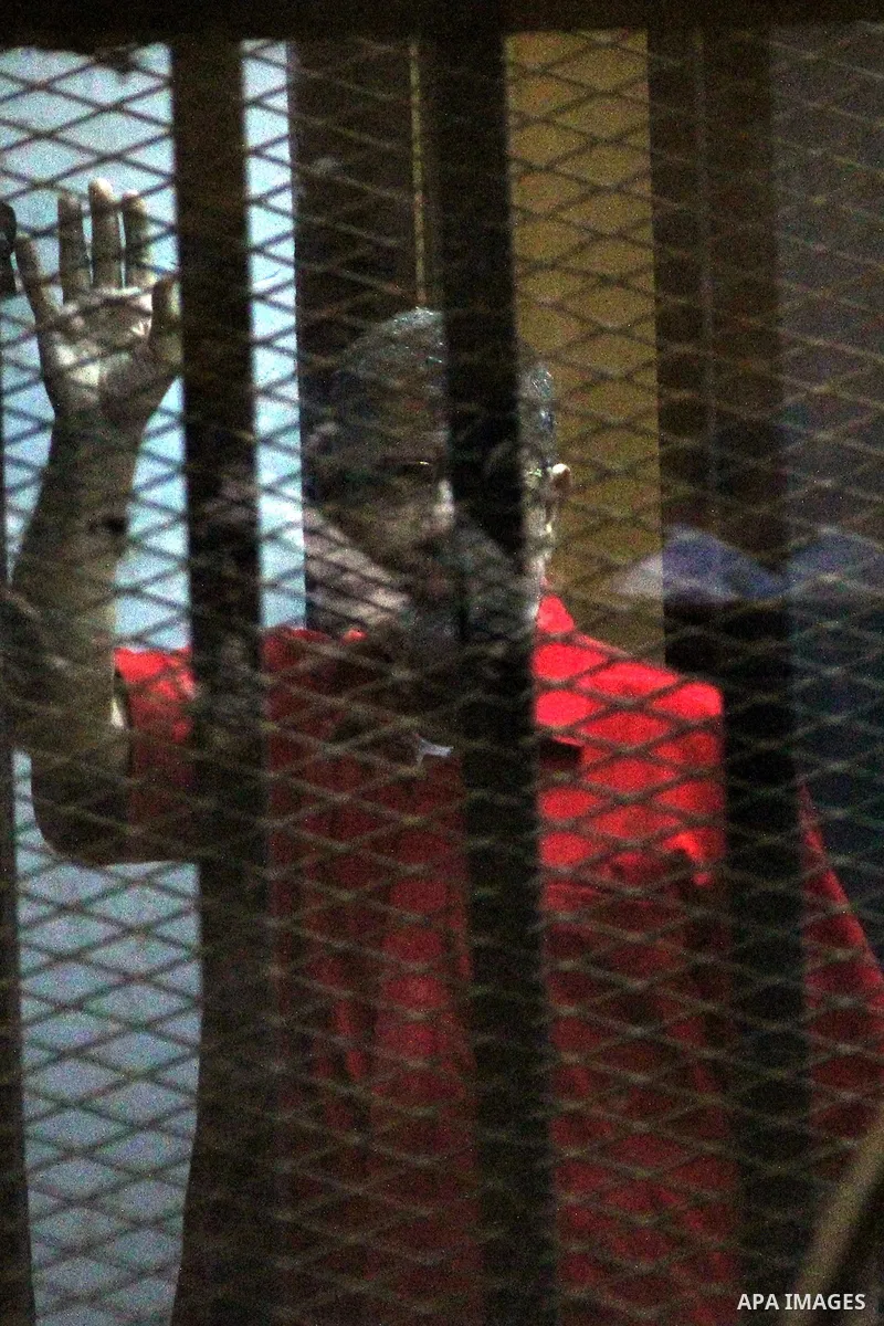 Ousted Egyptian president Mohammed Morsi waves as he stands behind bars during his trail in a court in Cairo on August 9, 2015. Cairo Criminal Court resumes on Saturday the trial of former Islamist president Mohamed Mors...