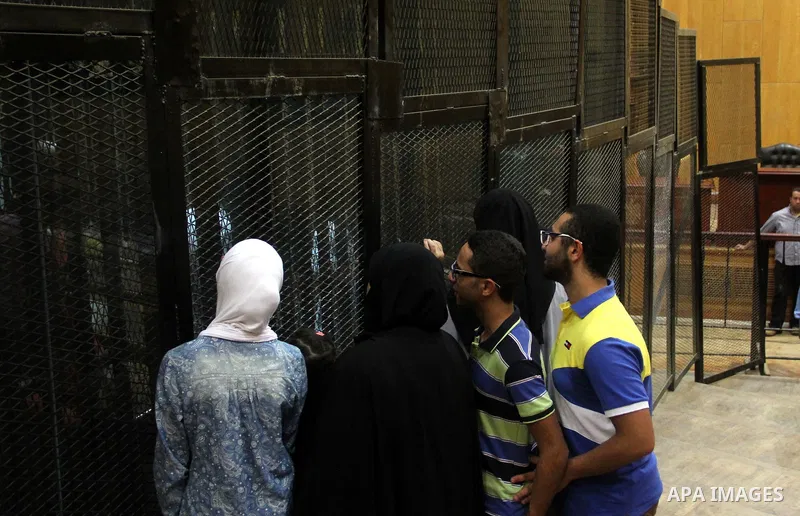 Relatives speak with Egyptian Muslim Brotherhood defendants as they stand behind the bars during their trial, along with ousted Islamist president Mohamed Morsi (unseen), in a court in Cairo on August 9, 2015. Cairo Crim...
