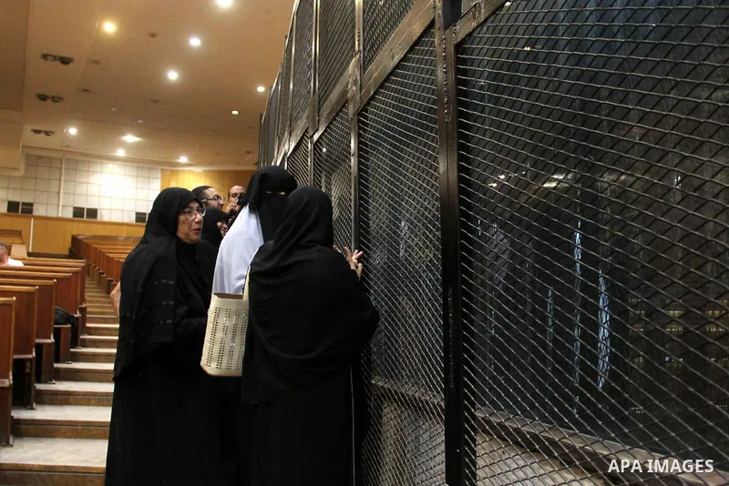 Relatives speak with Egyptian Muslim Brotherhood defendants as they stand behind the bars during their trial, along with ousted Islamist president Mohamed Morsi (unseen), in a court in Cairo on August 9, 2015. Cairo Crim...