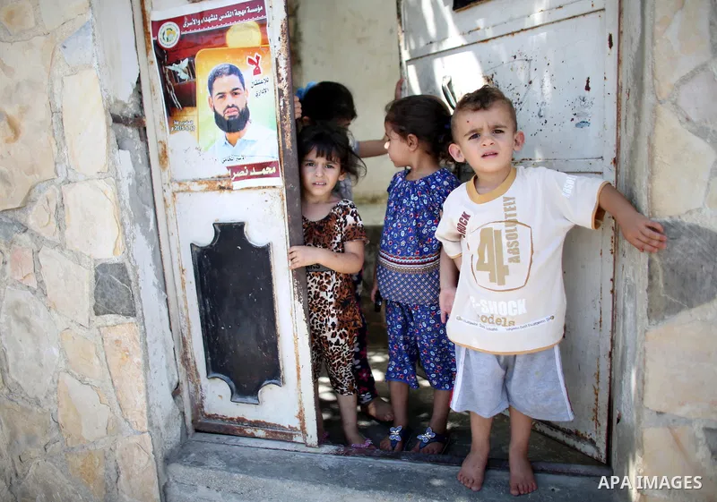 Relatives of Palestinian prisoner in Israeli jails Mohammad Allan, stand next to his portrait at the entrance of his house in the village of Ainabos, south of Nablus in the occupied West Bank, on August 9, 2015. The Isra...