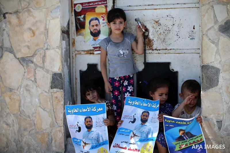 Relatives of Palestinian prisoner in Israeli jails Mohammad Allan, hold his portraits at the entrance of his house in the village of Ainabos, south of Nablus in the occupied West Bank, on August 9, 2015. The Israeli mili...
