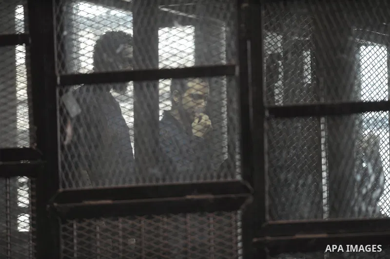 Egyptian Defendants on trial of of Egyptian radical Islamist Mohammed al-Zawahiri, the brother of Al-Qaeda chief Ayman al-Zawahiri sit behind bars, during their trial, at a court in Cairo on August 10, 2015. Photo by Amr...
