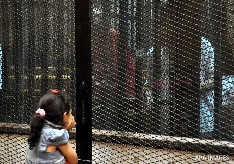The daughter of an Egyptian Muslim Brotherhood defendant, speaks with her father as he stands behind the bars during his trial, along with ousted Islamist president Mohamed Morsi (unseen), in a court in Cairo on August 1...