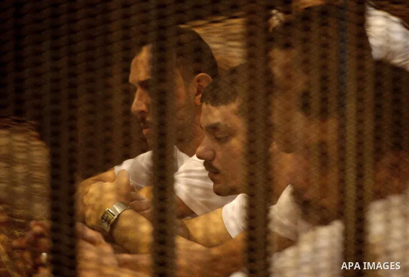 Egyptian defendants sit behind bars during their trial over a 2012 stadium riot in the canal city of Port Said that left 74 people dead, in Cairo on Augut 10, 2015. Cairo Criminal Court has set August 23 to issue its fin...