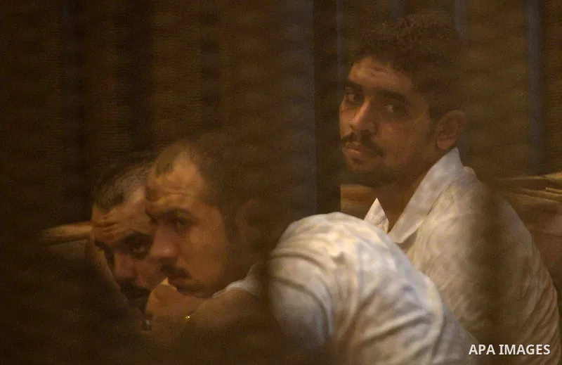 Egyptian defendants sit behind bars during their trial over a 2012 stadium riot in the canal city of Port Said that left 74 people dead, in Cairo on Augut 10, 2015. Cairo Criminal Court has set August 23 to issue its fin...