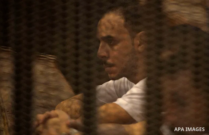 Egyptian defendants sit behind bars during their trial over a 2012 stadium riot in the canal city of Port Said that left 74 people dead, in Cairo on Augut 10, 2015. Cairo Criminal Court has set August 23 to issue its fin...