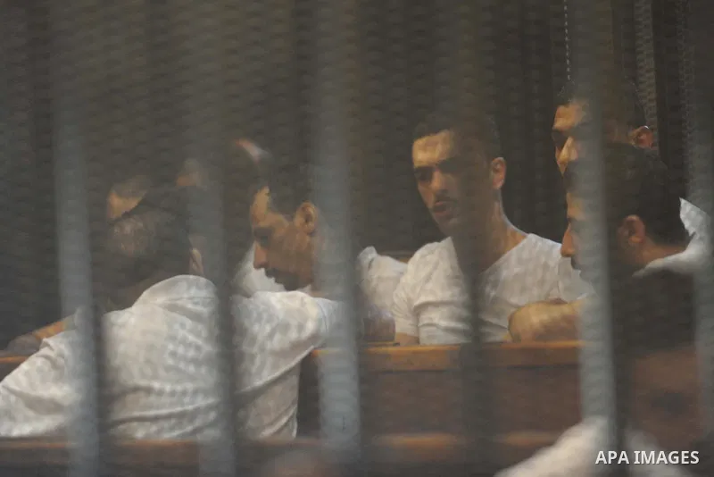 Egyptian defendants sit behind bars during their trial over a 2012 stadium riot in the canal city of Port Said that left 74 people dead, in Cairo on Augut 11, 2015. Cairo Criminal Court has set August 23 to issue its fin...