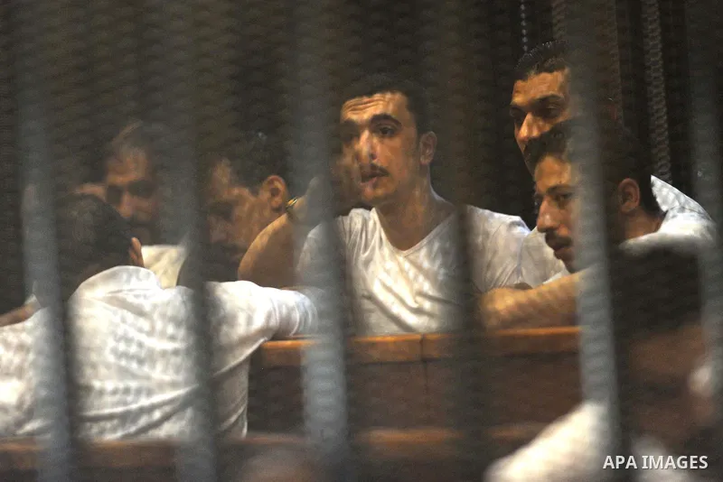 Egyptian defendants sit behind bars during their trial over a 2012 stadium riot in the canal city of Port Said that left 74 people dead, in Cairo on Augut 11, 2015. Cairo Criminal Court has set August 23 to issue its fin...