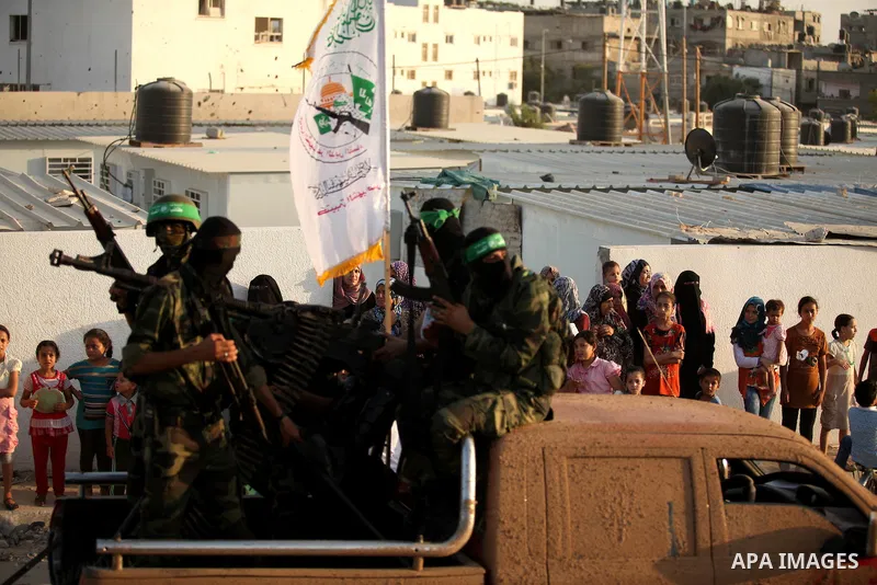Palestinians look on as members of Ezzedeen al-Qassam brigades, the armed wing of Hamas movement, take part in an anti-Israel parade in Beit Hanoun, in the northern Gaza Strip, on August 11, 2015. Photo by Ashraf Amra