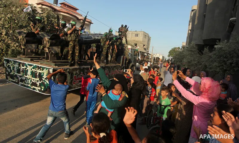 Palestinians look on as members of Ezzedeen al-Qassam brigades, the armed wing of Hamas movement, take part in an anti-Israel parade in Beit Hanoun, in the northern Gaza Strip, on August 11, 2015. Photo by Ashraf Amra