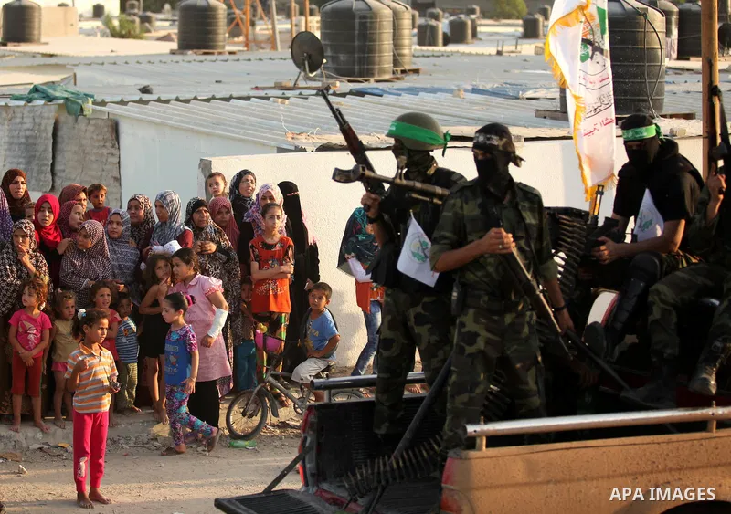 Palestinians look on as members of Ezzedeen al-Qassam brigades, the armed wing of Hamas movement, take part in an anti-Israel parade in Beit Hanoun, in the northern Gaza Strip, on August 11, 2015. Photo by Ashraf Amra