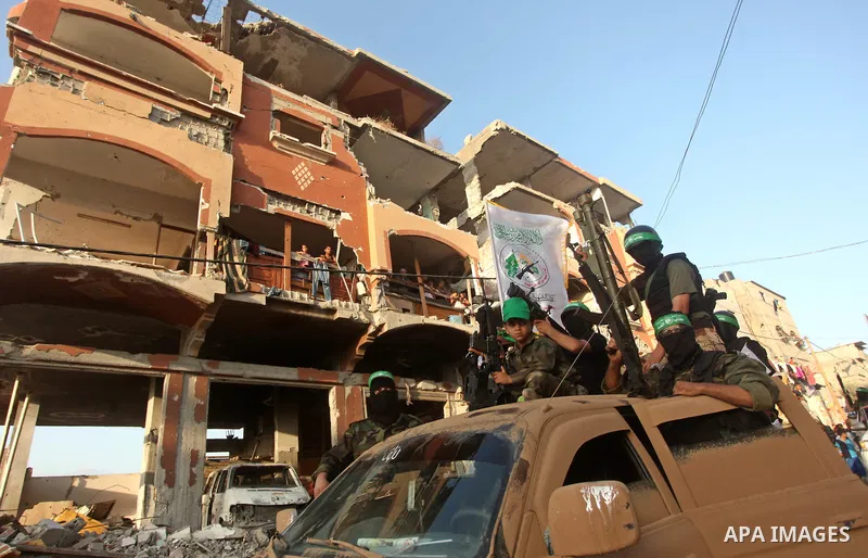 Palestinians look on as members of Ezzedeen al-Qassam brigades, the armed wing of Hamas movement, take part in an anti-Israel parade in Beit Hanoun, in the northern Gaza Strip, on August 11, 2015. Photo by Ashraf Amra