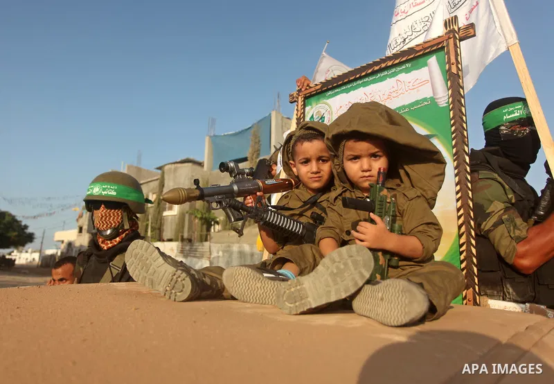 Palesltinian children sit on a military vehicle as members of Ezzedeen al-Qassam brigades, the armed wing of Hamas movement, take part in an anti-Israel parade in Beit Hanoun, in the northern Gaza Strip, on August 11, 20...