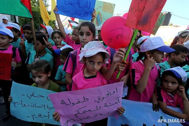 Palestinian children hold banners during a protest against the Israeli blockade on the Gaza Strip and demanding for opening the Rafah crossing, outside the United Nations headquarter in Gaza city on August 12, 2015. Phot...