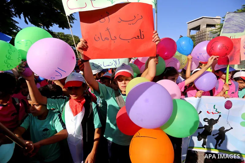 Palestinian children hold banners during a protest against the Israeli blockade on the Gaza Strip and demanding for opening the Rafah crossing, outside the United Nations headquarter in Gaza city on August 12, 2015. Phot...