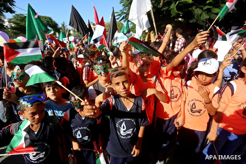 Palestinian children hold flags during a protest against the Israeli blockade on the Gaza Strip and demanding for opening the Rafah crossing, outside the United Nations headquarter in Gaza city on August 12, 2015. Photo...