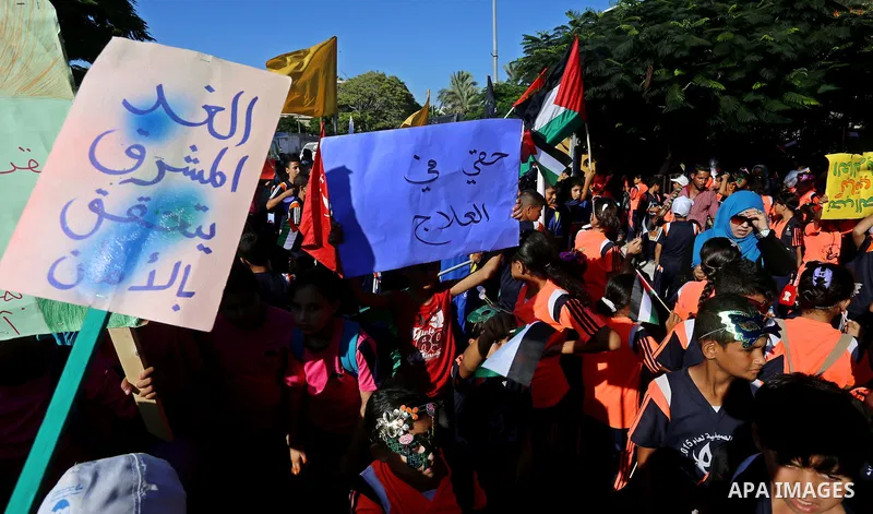 Palestinian children hold banners during a protest against the Israeli blockade on the Gaza Strip and demanding for opening the Rafah crossing, outside the United Nations headquarter in Gaza city on August 12, 2015. Phot...
