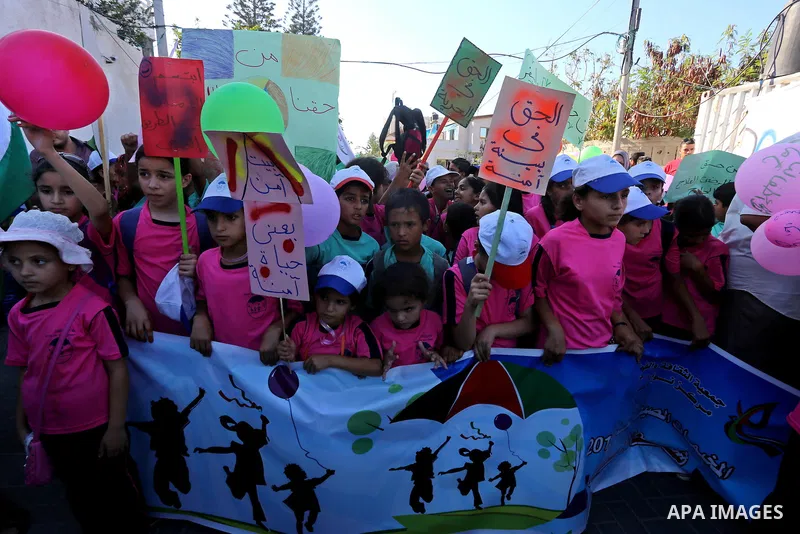 Palestinian children hold banners during a protest against the Israeli blockade on the Gaza Strip and demanding for opening the Rafah crossing, outside the United Nations headquarter in Gaza city on August 12, 2015. Phot...