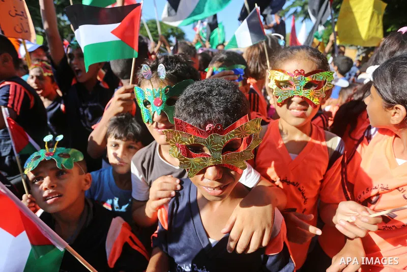 Palestinian children hold flags during a protest against the Israeli blockade on the Gaza Strip and demanding for opening the Rafah crossing, outside the United Nations headquarter in Gaza city on August 12, 2015. Photo...