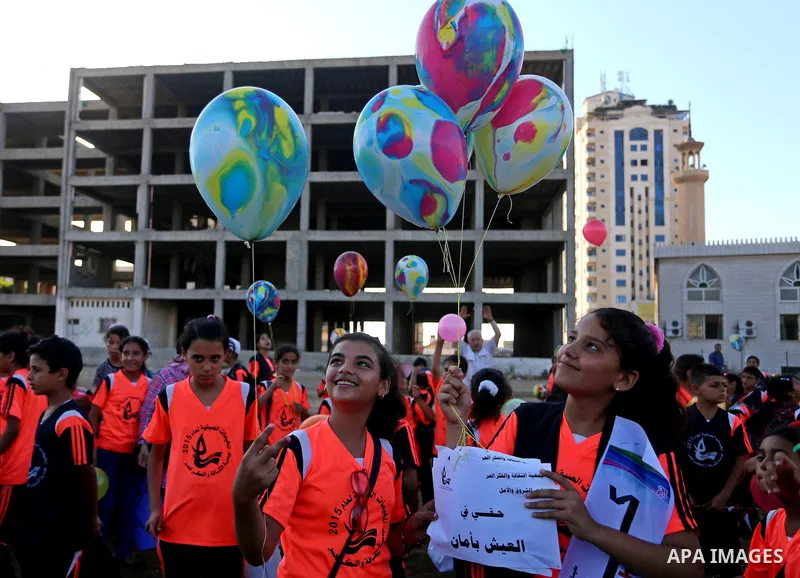 Palestinian children hold ballons during a protest against the Israeli blockade on the Gaza Strip and demanding for opening the Rafah crossing, outside the United Nations headquarter in Gaza city on August 12, 2015. Phot...