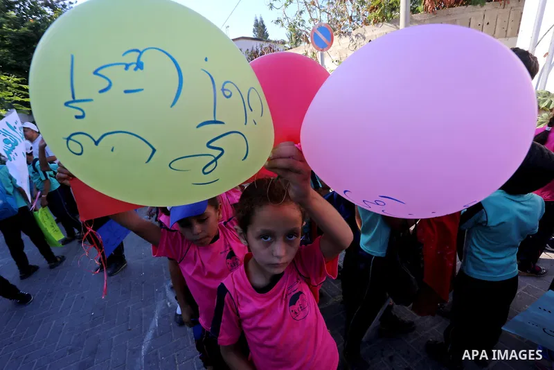 Palestinian children hold ballons during a protest against the Israeli blockade on the Gaza Strip and demanding for opening the Rafah crossing, outside the United Nations headquarter in Gaza city on August 12, 2015. Phot...