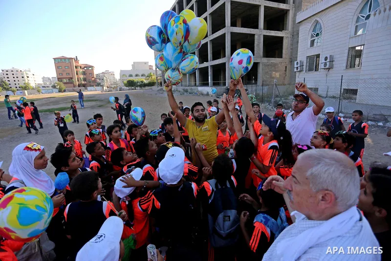 Palestinian children hold ballons during a protest against the Israeli blockade on the Gaza Strip and demanding for opening the Rafah crossing, outside the United Nations headquarter in Gaza city on August 12, 2015. Phot...