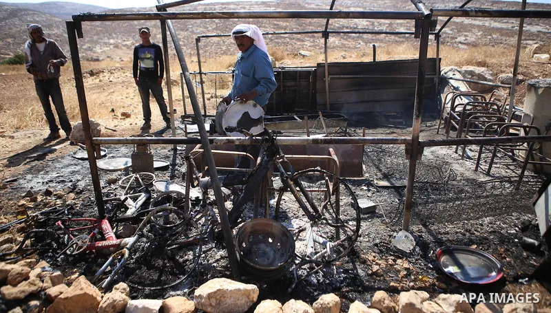 Palestinians inspect a tent burned by Jewish extremists in the area of Ein Samiya near Kafr Malik village in northern Ramallah, on August, 13, 2015. A group of Israeli settlers raided the village of Ein Samiya and threw...