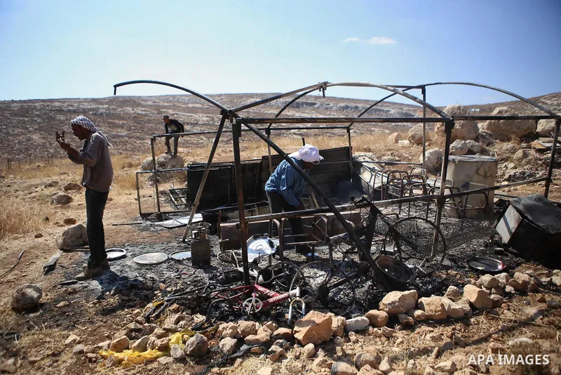 Palestinians inspect a tent burned by Jewish extremists in the area of Ein Samiya near Kafr Malik village in northern Ramallah, on August, 13, 2015. A group of Israeli settlers raided the village of Ein Samiya and threw...