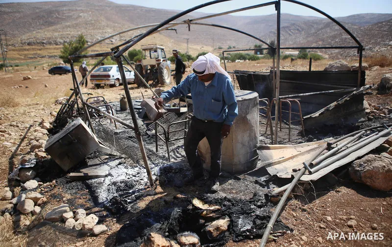 A Palestinian man inspects his a tent burned by Jewish extremists in the area of Ein Samiya near Kafr Malik village in northern Ramallah, on August, 13, 2015. A group of Israeli settlers raided the village of Ein Samiya...