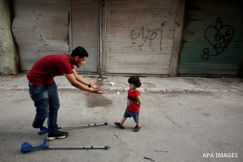 Nour, a 18-year-old Syrian man, plays wit his relative boy in a rebel-controlled area of Aleppo, on August 13, 2015. Nour lost his leg following a bomb barrel attack by forces of Syria's President Bashar al-Assad near hi...