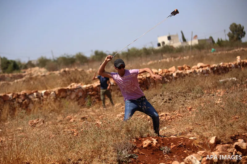 A protester hurls stones towards Israeli security forces during clashes following a demonstration in solidarity with prisoner, Mohammad Allan, allegedly being held in an Israeli jail, in the West Bank village of Nabi Sal...