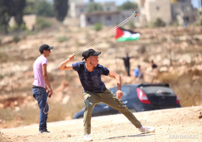 A protester hurls stones towards Israeli security forces during clashes following a demonstration in solidarity with prisoner, Mohammad Allan, allegedly being held in an Israeli jail, in the West Bank village of Nabi Sal...
