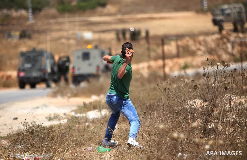 A protester throws stone towards Israeli security forces during clashes following a demonstration in solidarity with prisoner, Mohammad Allan, allegedly being held in an Israeli jail, in the West Bank village of Nabi Sal...