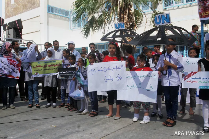 Palestinian children and teachers hold placards during a protest against the reduction of educational programs given by the United Nations Relief and Works Agency (UNRWA) at the Rafah refugee camp in the southern Gaza St...