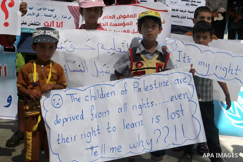 Palestinian children and teachers hold placards during a protest against the reduction of educational programs given by the United Nations Relief and Works Agency (UNRWA) at the Rafah refugee camp in the southern Gaza St...