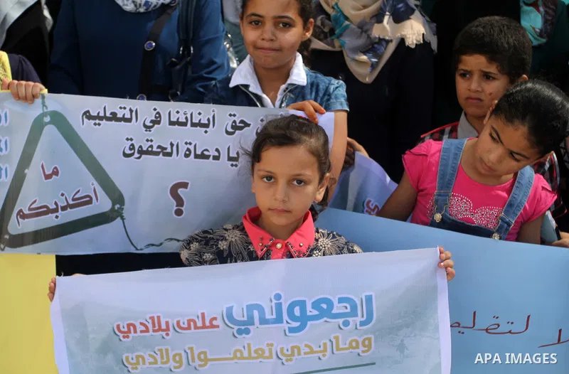 Palestinian children and teachers hold placards during a protest against the reduction of educational programs given by the United Nations Relief and Works Agency (UNRWA) at the Rafah refugee camp in the southern Gaza St...