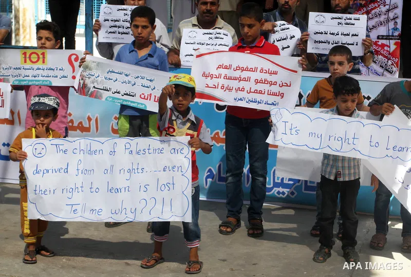 Palestinian children and teachers hold placards during a protest against the reduction of educational programs given by the United Nations Relief and Works Agency (UNRWA) at the Rafah refugee camp in the southern Gaza St...