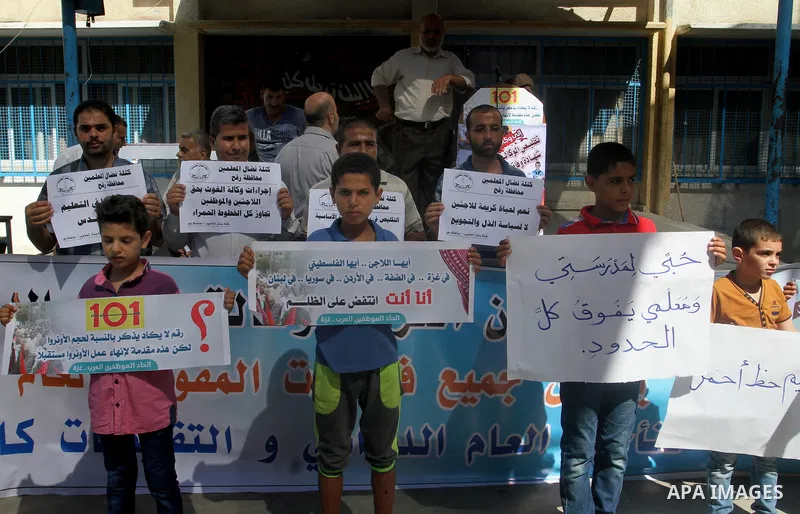 Palestinian children and teachers hold placards during a protest against the reduction of educational programs given by the United Nations Relief and Works Agency (UNRWA) at the Rafah refugee camp in the southern Gaza St...