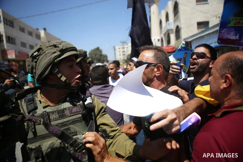 Palestinian protesters argue with Israeli soldiers during a demonstration in solidarity with Palestinian of prisoner Mohammad Allan, allegedly being held in an Israeli jail, at Israeli checkpoint of Hawara, near the West...