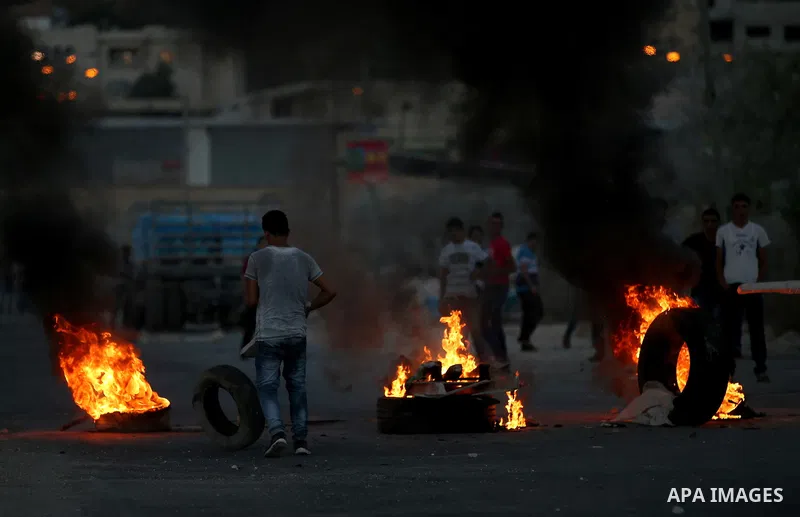 Palestinian protesters burn tires during clashes with Israeli security forces following killed of Rafiq Kamel Al-Taj, in the West Bank village of Beta near Nablus City on August 15, 2015. A police spokesperson said that...