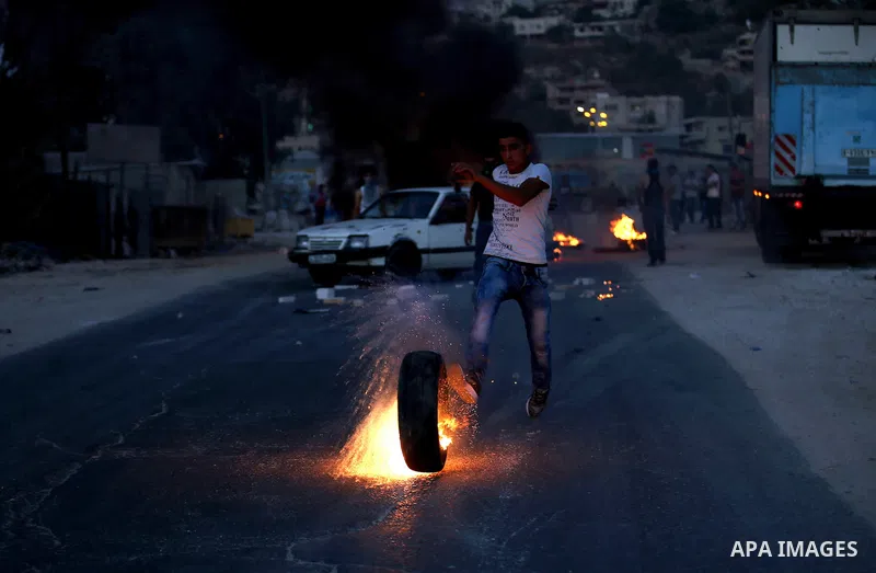 Palestinian protesters burn tires during clashes with Israeli security forces following killed of Rafiq Kamel Al-Taj, in the West Bank village of Beta near Nablus City on August 15, 2015. A police spokesperson said that...