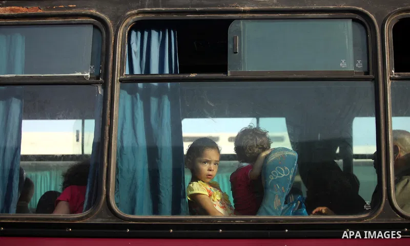 Palestinian children sitting in a bus react as they wait with their family to cross into Egypt at the Rafah border crossing between Egypt and the southern Gaza Strip on August 17, 2015. Egypt opened the Rafah border cros...