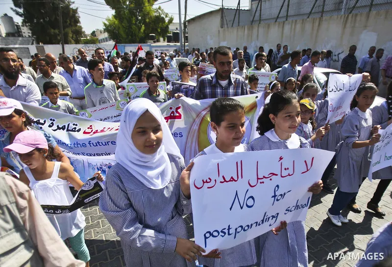 Palestinian children and teachers hold placards during a protest against the reduction of educational programs given by the United Nations Relief and Works Agency (UNRWA), in Gaza City August 17, 2015. Photo by Mohammed...