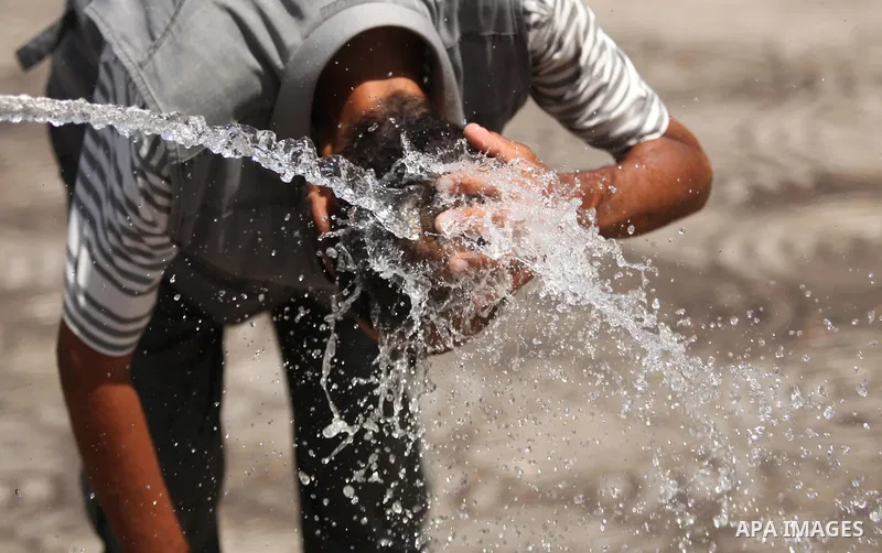 A Palestinian boy reacts as he splashes water on his head during a sweltering heat wave, in Gaza city on August 19, 2015. Photo by Ashraf Amra