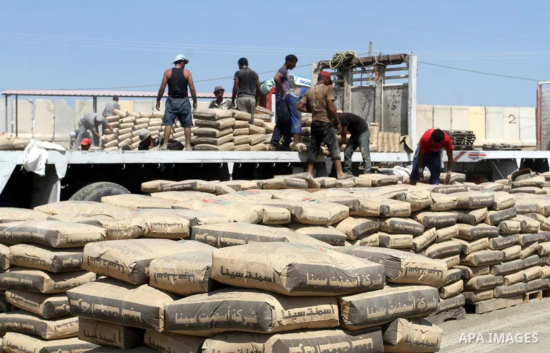 Palestinian workers offload a truck loaded with cement after it entered from Egypt through the Rafah border crossing in southern Gaza Strip, August 20, 2015. The authorities in Egypt have allowed 1,000 tons of cement and...
